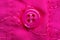 Macro photograph of a sewn-on pink button on a pink fabric with embroidery. Close-up detail of little girls dress