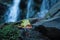 Macro photography of small autumnal colorful leaves lieing at moss stone at beautiful waterfall background. Flowing