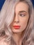 Macro of Platinum Blonde Hair Woman With Blue Eyes and Augmented Lips, Painted With Coral Lipstick, Looking Away