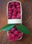 Macro raspberries in a basket with green leaf