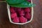 Macro raspberries in a basket with green leaf