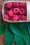 Macro raspberries in a basket with green leaf