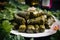 Macro shot of beautifully arranged stuffed grape leaves with tantalizing filling spilling out onto a plate surrounded by vibrant