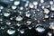 Macro shot of blue shimmering water drops on a shiny dark background