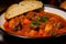 Macro shot of a bowl of goulash with beef, potatoes, and carrots, simmered in a rich and flavorful tomato-based sauce