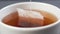 Macro shot of brewing a black tea bag in a white cup. Dipping a paper teabag