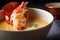 Macro shot of a cooked lobster tail in a bowl of thick and creamy lobster bisque soup