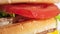 Macro shot delicious red tomato slice in appetizing fresh burger rotating shot