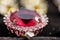 Macro shot of golden pendant with kunzite stone and tourmaline on black, sparkling, sunny background.