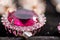 Macro shot of golden pendant with kunzite stone and tourmaline on black, sparkling, sunny background.