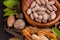 Macro shot of herbal tablets in a wooden utensil with spices and green herbs on black background. Ayurveda concept