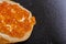 Macro shot of a mouthwatering sandwich with butter and red caviar on a black plate