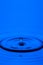 Macro Shot of One Blue Water Droplet Over Tranquil Water Surface