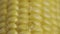 Macro shot of row ripe yellow corn grains along which trickle of thick viscous honey or oil flows. Sweet nectar envelops