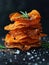 Macro shot of a stack of sweet potato chips adorned with rosemary sprig and sea salt, on a dark atmospheric background