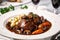 Macro shot of succulent Coq au Vin, a traditional French dish with a rich red wine sauce, served on a white porcelain plate