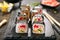 Macro shot of sushi roll in Japanese restaurant with chopsticks closeup. Sushi rolls with rice, fried salmon, flying fish caviar,