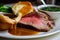 macro shot of tender slices of roast beef, accompanied by a single golden-brown Yorkshire pudding and a side of rich