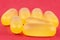 Macro shot of yellow gelatin capsules, isolated on a red background.