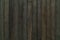 Macro texture of vertical lacquered bamboo wood planks with striped pattern. Background of greenish black bamboo boards surface.
