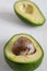 Macro top view of two half avocados with seed, selective focus, on white wooden table