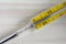 Macro top view of yellow mercury medical thermometer on white wooden background