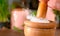 MACRO: Unrecognizable woman crushes a chunk of rock salt with a wooden pestle.