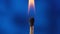Macro video captures the moment of ignition of the match and its flame on a blue background. From the flare up to the
