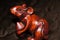 Macro view of a cute wooden carved polished brown mouse on a dark material.