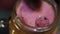 Macro view of hand putting single raspberry on surface of pink mass in glass jar