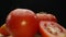 Macrography, slices of tomato placed on board with black background. Comestible.