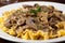 Macron close-up of tender beef strips smothered in rich, creamy stroganoff sauce with sauteed mushrooms