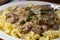 Macron close-up of tender beef strips smothered in rich, creamy stroganoff sauce with sauteed mushrooms