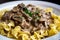 Macron close-up of tender beef strips smothered in rich, creamy stroganoff sauce with sauteed mushrooms