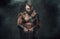 Mad scandinavian warrior with huge axe in dark smokey background
