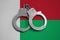 Madagascar flag and police handcuffs. The concept of observance of the law in the country and protection from crime