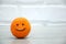 Madarin with a painted smile on a wooden table against a loft background.