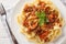 Mafaldine or reginette is a type of ribbon-shaped pasta with bolognese sauce and basil closeup on the plate on the wooden table.