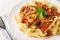 Mafaldine or reginette is a type of ribbon-shaped pasta with bolognese sauce and basil closeup on the plate on the wooden table.