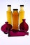 Magenta and clear bottles filled with brown liquid on white background