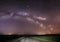 Magenta Night Starry Sky Above Country Asphalt Road In Countryside And Green Field. Night View Of Natural Glowing Stars