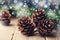 Magic composition with pine cones and fir tree branch on rustic wooden table. Christmas card. Snow effect.