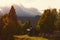 Magic mountain autumn landscape. Wooden shelter in the autumn color forest. High mountain peaks with thunderclouds. Dramatic scene