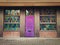 Magic wooden purple door. Beautiful house facade with colorful windows glass and pavement yard. Vintage architecture