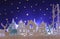 Magical Christmas paper cut winter background landscape with houses, trees, deer and snow in front of night starry sky background.