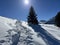 A magical play of sunlight and shadow during the alpine winter on the snowy slopes above the mountine resort of Arosa