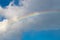 Magical rainbow on cloudy blue sky