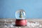 Magical snow globe with Christmas tree on wooden table