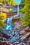 Magical stunning three tiered waterfalls from below pouring over layers of cliffs in peak New York fall foliage