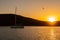 Magical, vibrant orange sunset over the hill and Mediterranean Sea with a dark sailing boat,bird flying, in a bay on Rineja,Greece